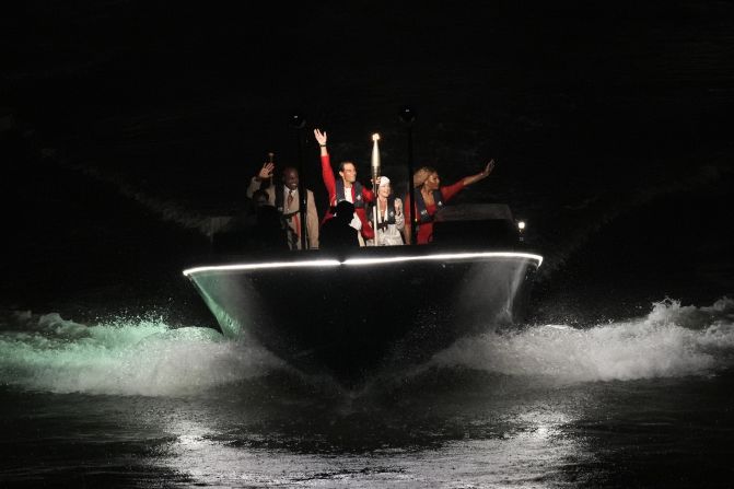 Tennis star Rafael Nadal carries the Olympic flame aboard a boat with a few famous former Olympians: from left, Carl Lewis, Nadia Comăneci and Serena Williams.