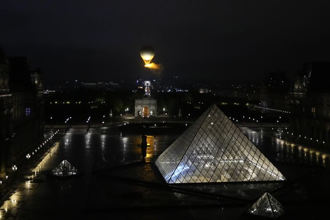 The lit cauldron is seen from the Louvre.