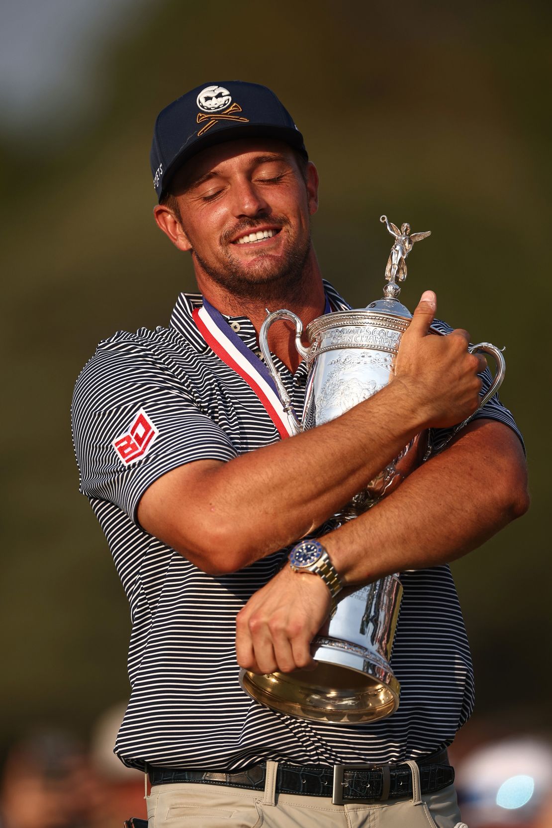 DeChambeau clutches the trophy.