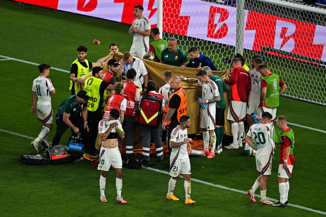 Players and stewards hold sheets to hide Varga while he receives medical treatment.