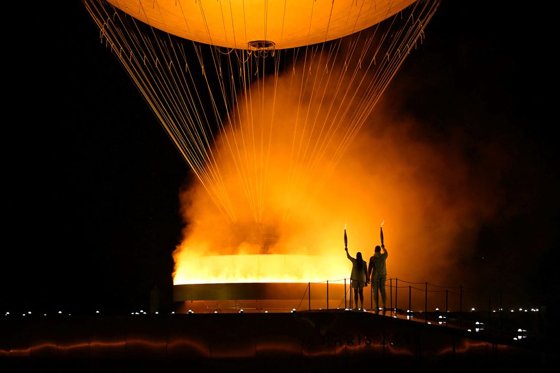 The torchbearers French former sprinter Marie-Jose Perec and French judoka Teddy Riner arrive to light the Olympic cauldron during the opening ceremony of the Paris 2024 Olympic Games in Paris on July 26, 2024.