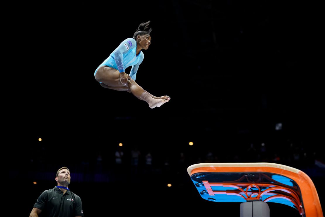 Simone Biles of Team United States performs her new jump routine 'Biles II' Yurchenko double pike vault with coach Laurent Landi on the mat for assistance on Vault during Women's Qualifications on Day Two of the FIG Artistic Gymnastics World Championships at the Antwerp Sportpaleis on October 01, 2023 in Antwerp, Belgium.