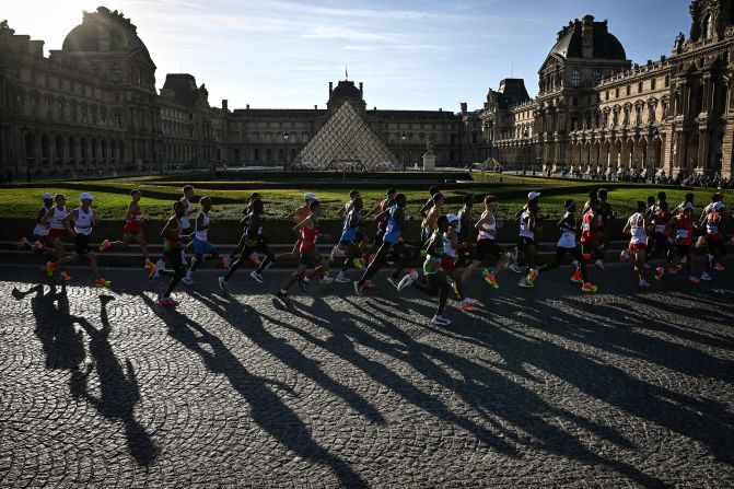 Marathoners run past the Louvre on August 10.