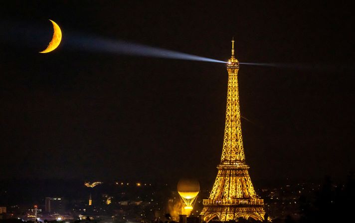 The moon shines above the Eiffel Tower and Olympic cauldron on Friday, August 9.