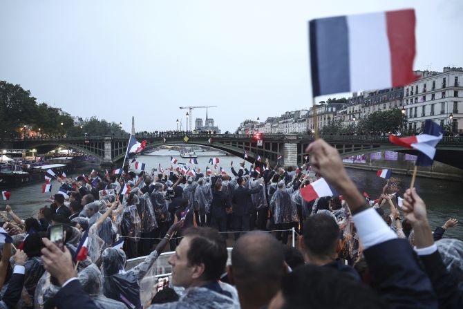 French athletes wave flags as they travel down the Seine during the Parade of Nations.