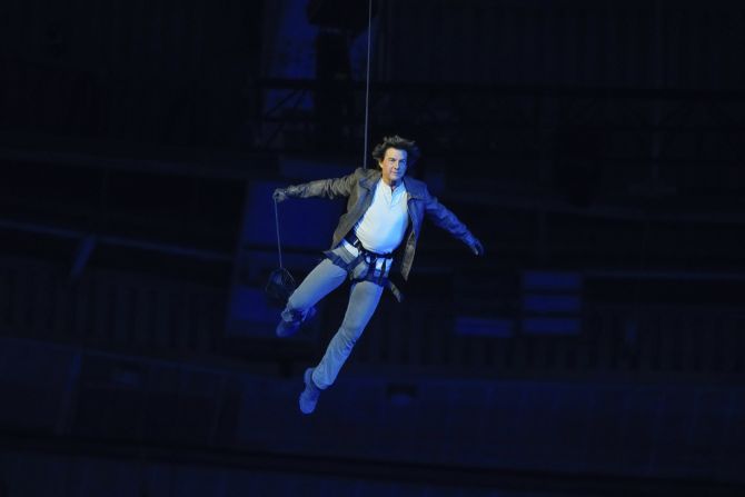 Actor Tom Cruise is lowered onto the floor of the Stade de France after jumping off the stadium's roof during the closing ceremony. He took the Olympic flag from Los Angeles Karen Bass and rode off on a motorcyle.