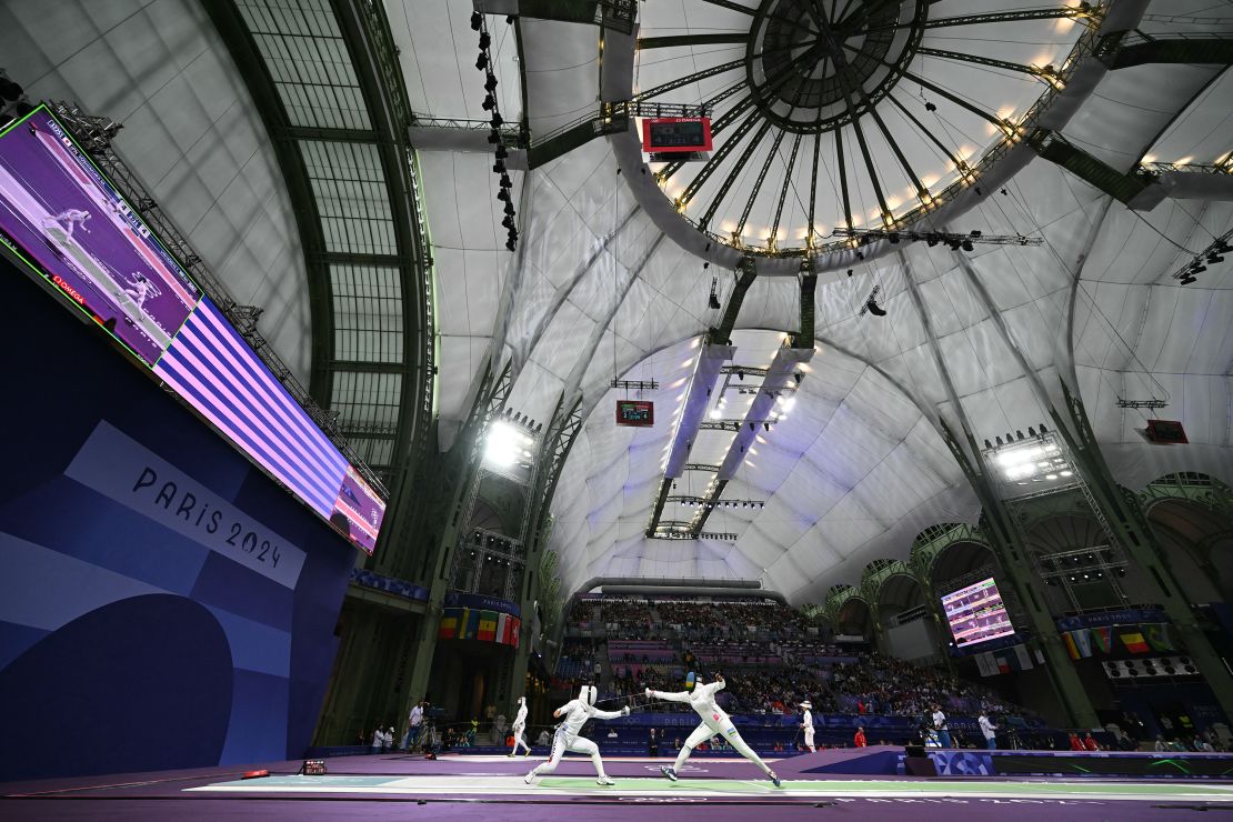 Japan's Yoshimura Miho (center L) competes against Rwanda's Tufaha Uwihoreye in the women's epee individual round of 64 bout during the Paris 2024 Olympic Games at the Grand Palais in Paris, on July 27, 2024.