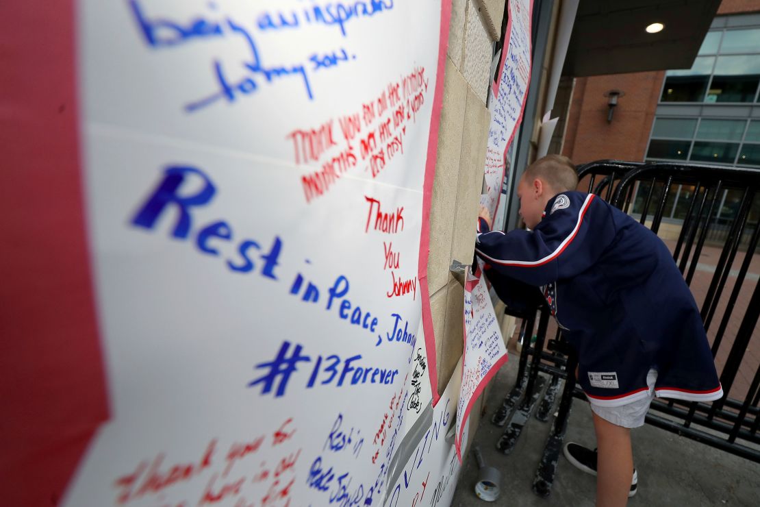 Gavin Rose signs a number 13 at a memorial set up by fans for Blue Jackets hockey player Johnny Gaudreau in Columbus, Ohio, on August 30.