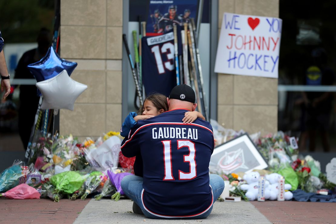 Shiloh Rivera, facing, mourns with Hylas Stemen of Columbus, on Friday at the makeshift memorial set up by fans for Blue Jackets hockey player Johnny Gaudreau in Columbus, Ohio, on Friday.