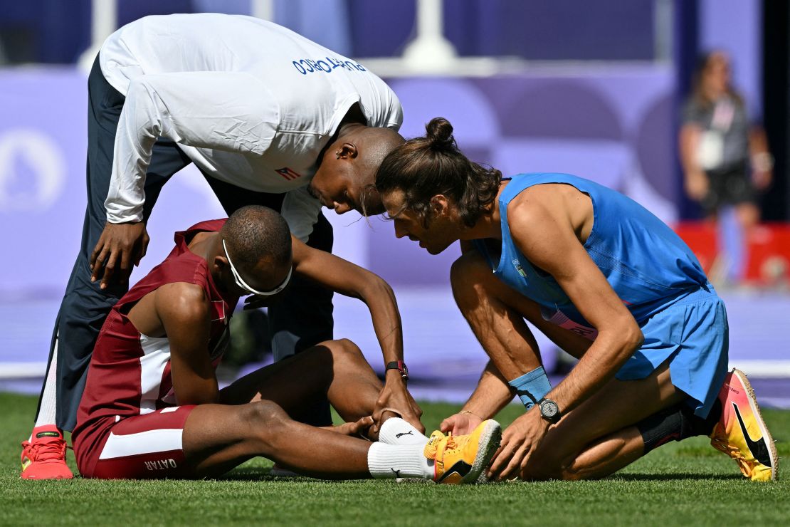 Tamberi checks on Barshim holding his calf following an injury on August 7.