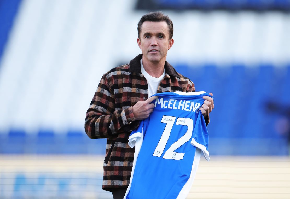 BIRMINGHAM, ENGLAND - SEPTEMBER 16: Rob McElhenney, Co-Owner of Wrexham AFC, looks on as he is seen holding aBirmingham City shirt featuring the name "McElhenney" and the number 12 prior to the Sky Bet League One match between Birmingham City FC and Wrexham AFC at St Andrew’s at Knighthead Park on September 16, 2024 in Birmingham, England. (Photo by Alex Pantling/Getty Images)