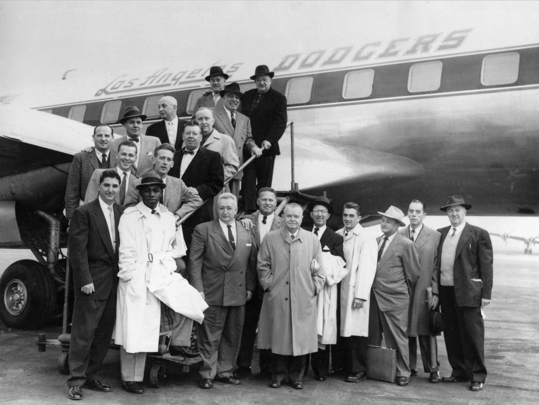 Brooklyn Dodgers officials and employees pose in front of the club's plane at La Guardia in New York, before taking off for Los Angeles on October 23, 1957.