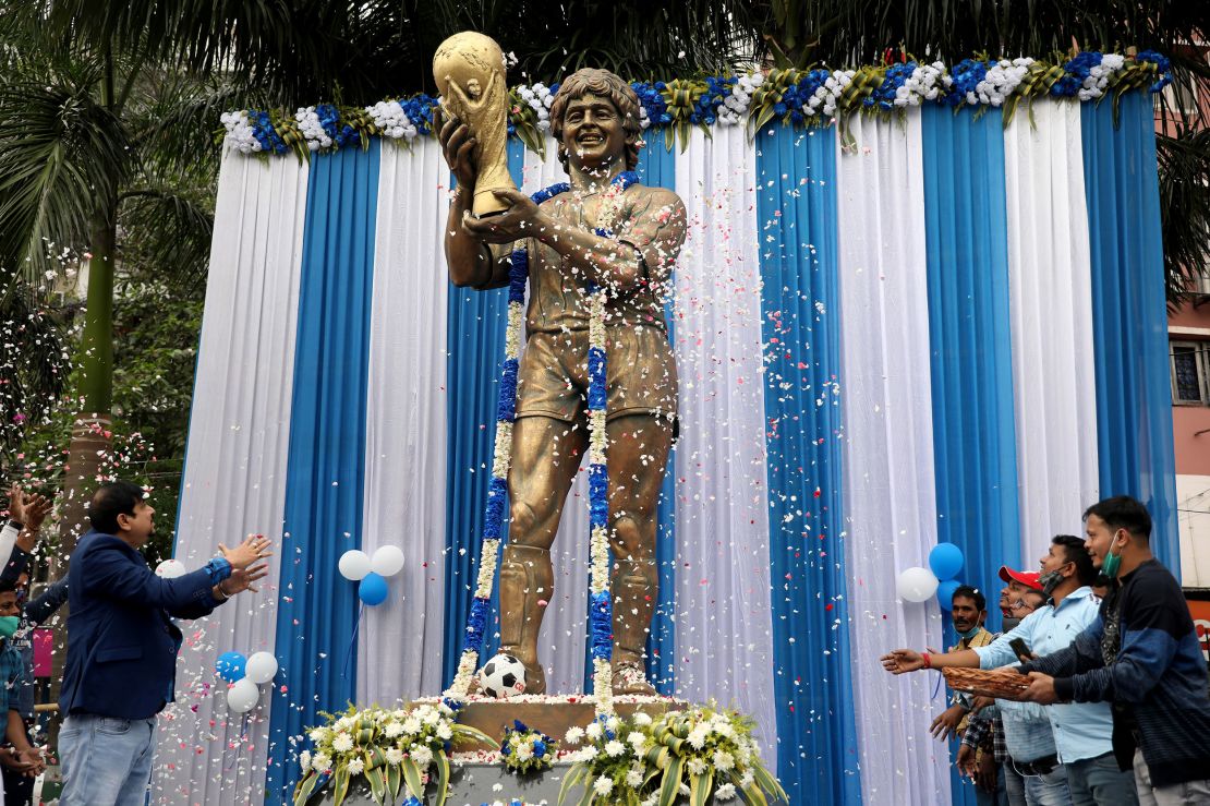 People shower petals on Diego Maradona's statue in Kolkata during a prayer meeting to pay tribute to him after his death in November 2020.