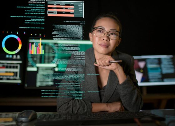 A person studying a see-through display of various charts and graphs.