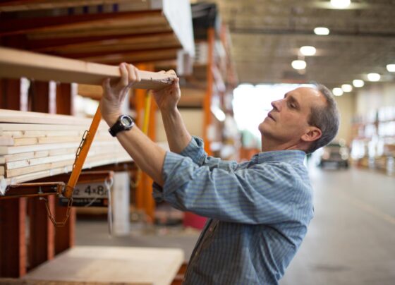 A person moving lumber off a shelf at a warehouse.