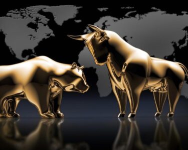 Golden bull and bear statues in front of a global map.