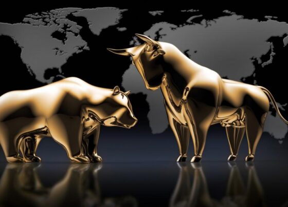 Golden bull and bear statues in front of a global map.