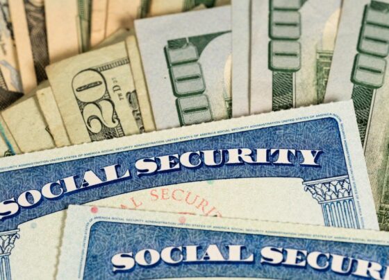 Two Social Security cards laying on a pile of cash.