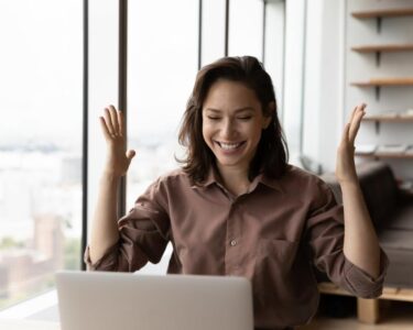 An investor smiles and looks at something on a laptop in an office.