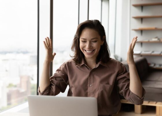 An investor smiles and looks at something on a laptop in an office.