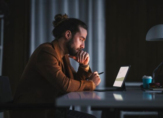 Person deep in thought while looking at graphs on a tablet computer.