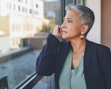 A woman looks out of the window in her office and contemplates whether she can afford to retire at 66.