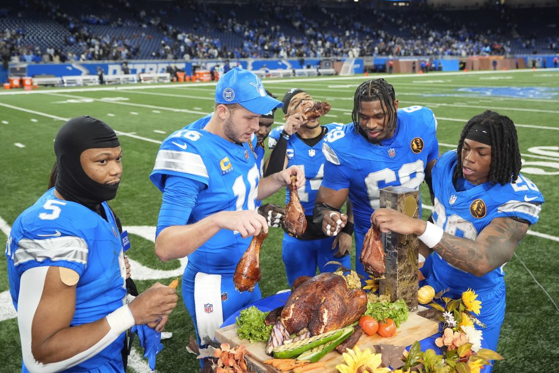 Lions players celebrate beating the Bears by eating turkey with David Montgomery (left) munching on a carrot.