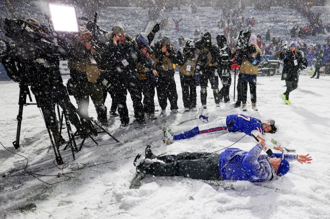 Buffalo Bills quarterback Josh Allen and head coach Sean McDermott make snow angels while being interviewed after the Bills defeated the San Francisco 49ers at Highmark Stadium in Orchard Park, New York, on Sunday, December 1. Crews and volunteers assisted with removing snow from the field earlier in the day, however, the snow kept falling throughout the game.