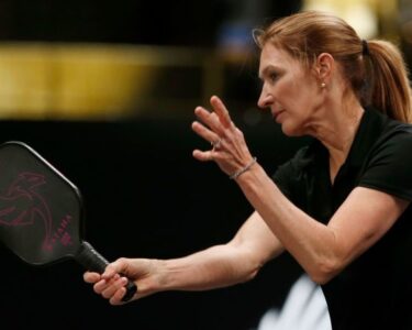 Graf returns a volley from John McEnroe as teammate Andre Agassi looks on during Pickleball Slam 2.