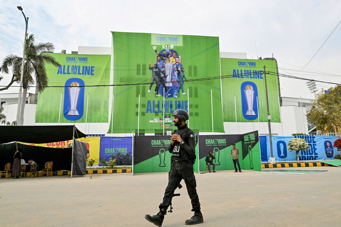 A police commando walks past Champions Trophy posters outside the National Stadium in Karachi, Pakistan on February 17, 2025.