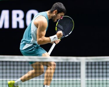 Alcaraz plays a serve against de Minaur.